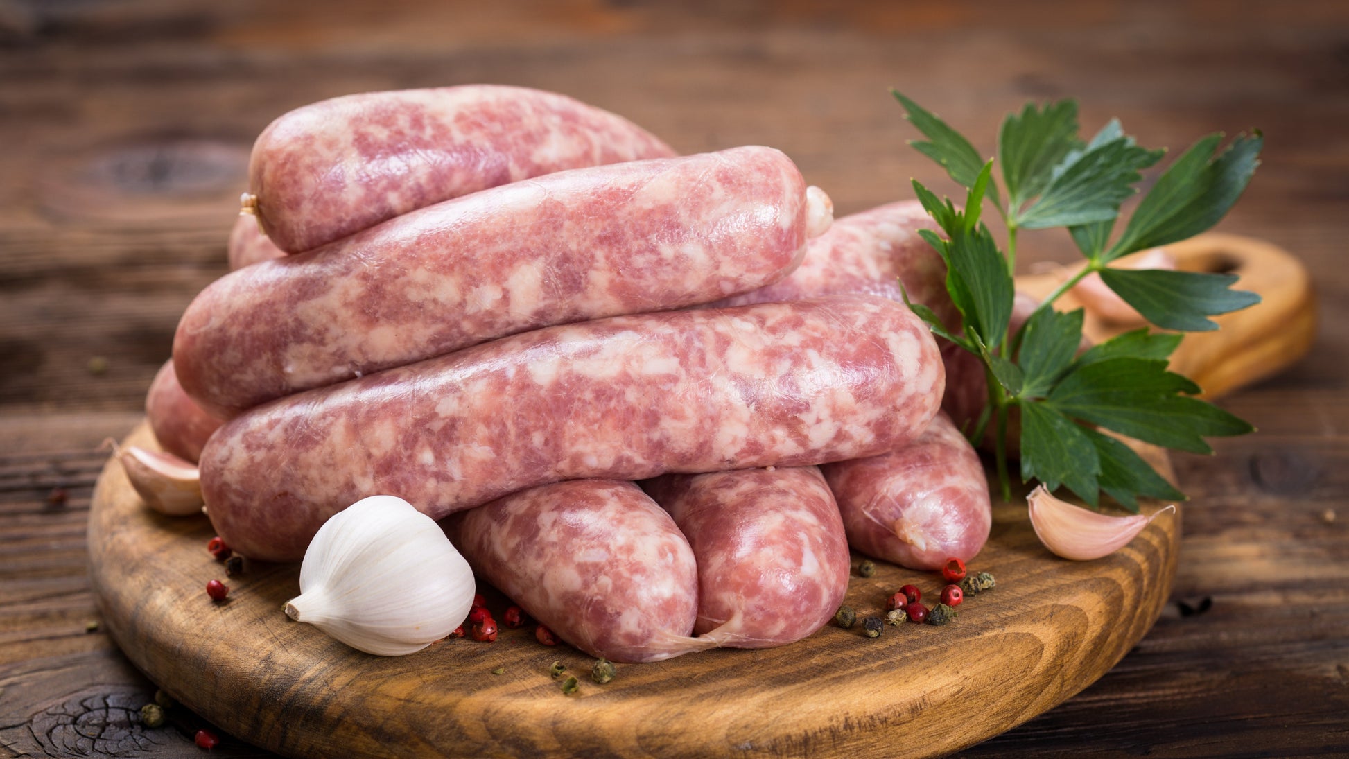 linked pork sausages displayed on a cutting board with garlic and fresh parsley